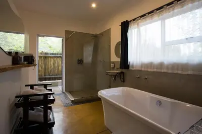 a bathroom with a tub and a shower with a window at isiLimela Game Lodge in Hoedspruit