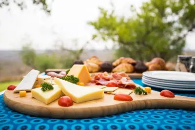 a cutting board with cheese and other foods on a table at isiLimela Game Lodge in Hoedspruit