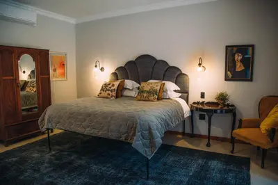 a bedroom with a large bed and a chair at The Bohemian Guesthouse in Tzaneen