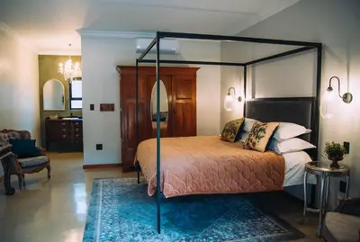 a bedroom with a canopy bed with a blue rug at The Bohemian Guesthouse in Tzaneen