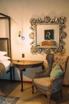 a room with a table and a chair and a mirror at The Bohemian Guesthouse in Tzaneen