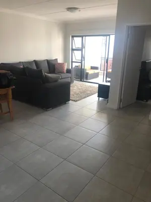 a living room with a black couch and a tile floor at A Coastal/island experience at a Large 2 bed apartment at a Crystal Lagoon Estate. in Pretoria