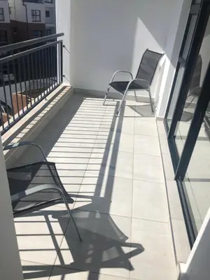 two chairs sitting on a balcony with their shadows at A Coastal/island experience at a Large 2 bed apartment at a Crystal Lagoon Estate. in Pretoria