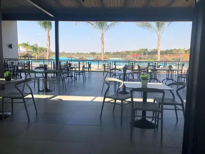 a patio with tables and chairs and a pool at A Coastal/island experience at a Large 2 bed apartment at a Crystal Lagoon Estate. in Pretoria