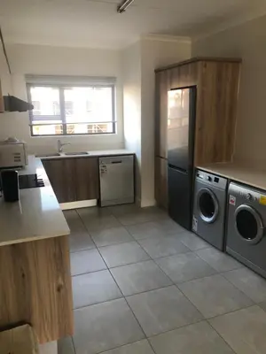 a kitchen with a washer and dryer in it at A Coastal/island experience at a Large 2 bed apartment at a Crystal Lagoon Estate. in Pretoria