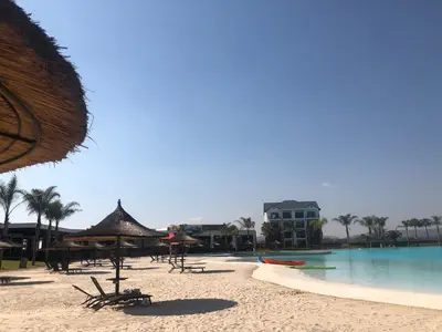 a beach with a pool and some chairs and a building at A Coastal/island experience at a Large 2 bed apartment at a Crystal Lagoon Estate. in Pretoria