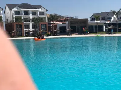 a large pool of blue water with people in a kayak at A Coastal/island experience at a Large 2 bed apartment at a Crystal Lagoon Estate. in Pretoria