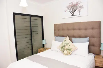 a bedroom with a white bed with a brown headboard at The Blyde in Pretoria