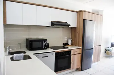 a kitchen with a sink and a refrigerator at The Blyde in Pretoria