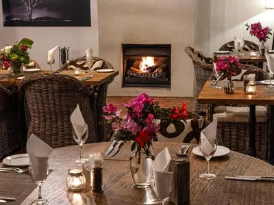 a dining room with a table and a fireplace at Kings Walden Garden Manor in Tzaneen