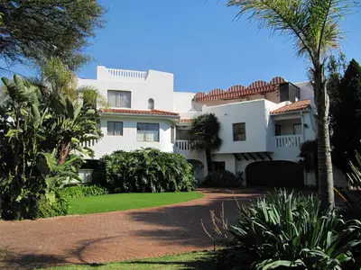 a white house with palm trees and a driveway at Kleineweide Boutique Estate in Pretoria