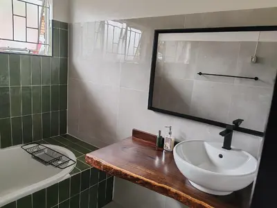 a bathroom with a sink and a mirror and a tub at Boh- House in Graskop