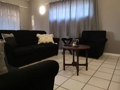 a living room with two black couches and a table at Boh- House in Graskop