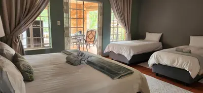 a bedroom with two beds and a balcony at Mahogany Guesthouse Mbombela in Nelspruit