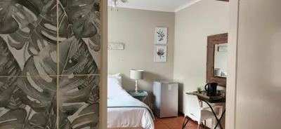 a room with a bedroom with a bed and a mirror at Mahogany Guesthouse Mbombela in Nelspruit