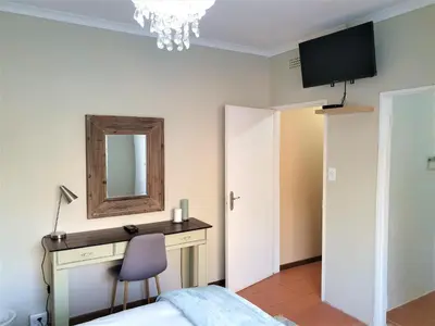 a bedroom with a desk and a mirror and a chair at Mahogany Guesthouse Mbombela in Nelspruit