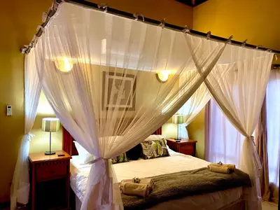 a bedroom with a canopy bed with white curtains at The Bush Hut in Hoedspruit