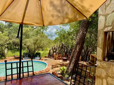 an umbrella on a deck next to a swimming pool at The Bush Hut in Hoedspruit