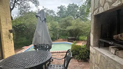a table with an umbrella next to a swimming pool at The Bush Hut in Hoedspruit