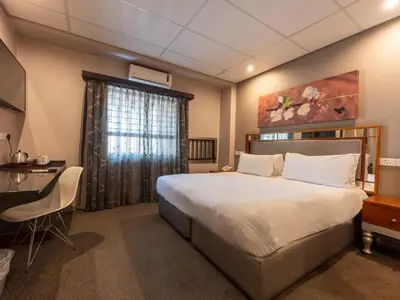 a bedroom with a large bed and a desk at ANEW Hotel Hatfield Pretoria in Pretoria
