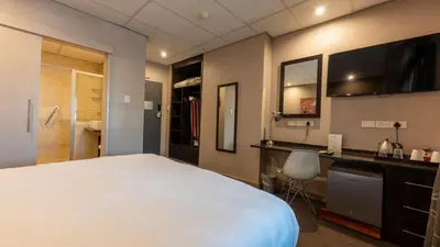 a bedroom with a large white bed and a desk at ANEW Hotel Hatfield Pretoria in Pretoria