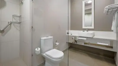 a white bathroom with a toilet and a sink at ANEW Hotel Hatfield Pretoria in Pretoria