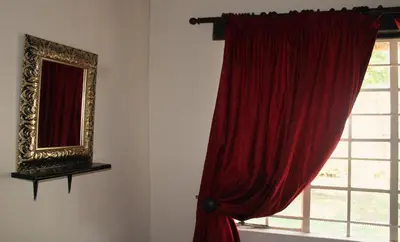 a window with a red curtain and a mirror at OPPIBERG GUEST HOUSE and SPA in Hartbeespoort
