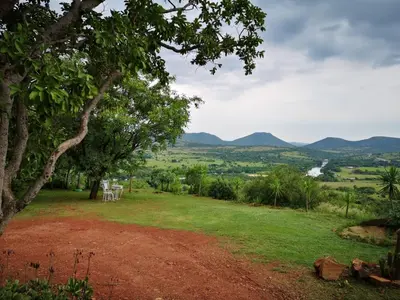 a view of a field with mountains in the distance at OPPIBERG GUEST HOUSE and SPA in Hartbeespoort