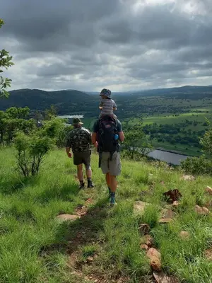 a man with a child on his back walking up a hill at OPPIBERG GUEST HOUSE and SPA in Hartbeespoort