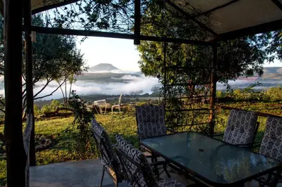 a table and chairs on a porch with a view at OPPIBERG GUEST HOUSE and SPA in Hartbeespoort