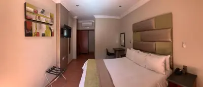 a hotel room with a bed and a desk at Polokwane Lodge in Polokwane