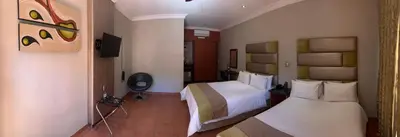 a hotel room with two beds and a television at Polokwane Lodge in Polokwane