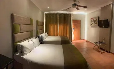 a bedroom with two beds and a ceiling fan at Polokwane Lodge in Polokwane