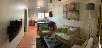 a living room with a couch and a kitchen at Polokwane Lodge in Polokwane