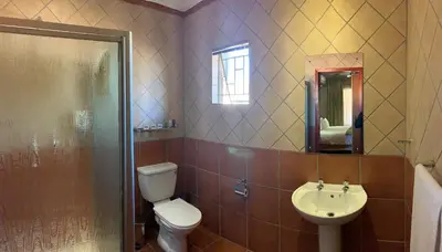 a bathroom with a toilet and a sink and a shower at Polokwane Lodge in Polokwane