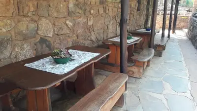 two tables and benches in front of a stone wall at Echo Caves in Ohrigstad