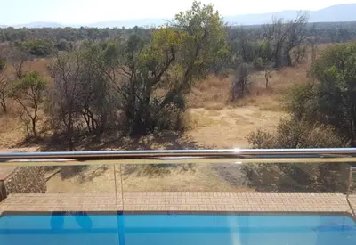 a view from the top of a pool with a view of a field at Zebula 8 Bedroom Lodge – IV1 in Mabula