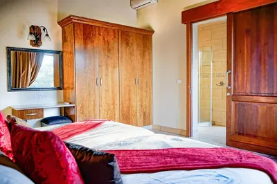 a bedroom with a large bed and a wooden cabinet at Zebula 8 Bedroom Lodge – IV1 in Mabula