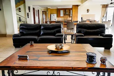 a living room with black leather couches and a table at Zebula 8 Bedroom Lodge – IV1 in Mabula