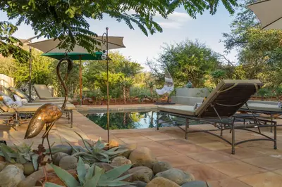 a patio with a pool and chairs and an umbrella at Ukuthula Bush Lodge in Hoedspruit