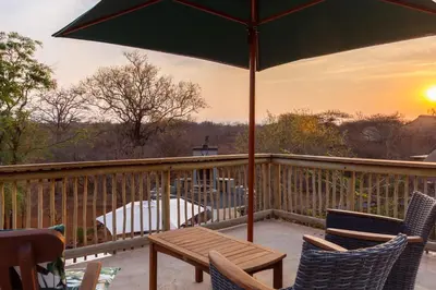 a deck with chairs and a table and an umbrella at Ukuthula Bush Lodge in Hoedspruit