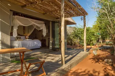 a porch of a house with a bed and a table at Ukuthula Bush Lodge in Hoedspruit
