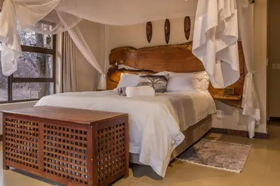 a bedroom with a large bed with a wooden headboard at Ukuthula Bush Lodge in Hoedspruit