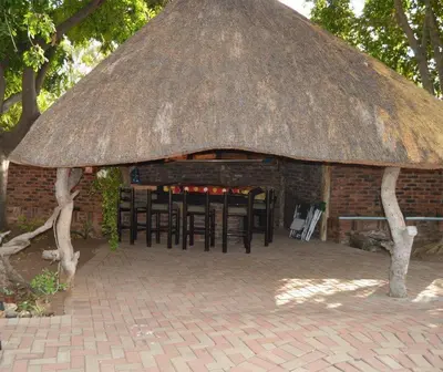 a brick building with chairs and a thatch roof at Villa Danamara in Phalaborwa