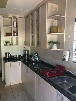 a kitchen with white cabinets and a black counter top at Villa Danamara in Phalaborwa