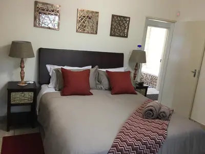 a bedroom with a large white bed with red pillows at Villa Danamara in Phalaborwa