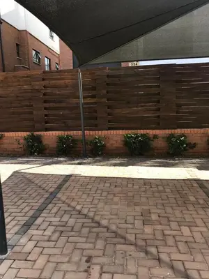 a brick sidewalk with a wooden fence in front of a building at The Blyde, an impeccable blissful getaway (Balwin properties) in Pretoria