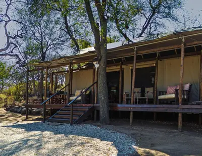 a house with a tree in front of it at Abelana Safari Camp in Phalaborwa