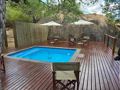 a pool on a wooden deck with chairs and umbrellas at Abelana Safari Camp in Phalaborwa