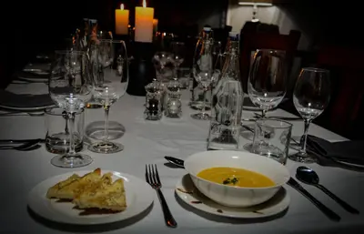 a table with a bowl of soup and wine glasses at Abelana Safari Camp in Phalaborwa